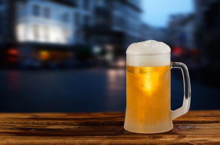 cold glass mug of beer with foam on the background of the streetの写真素材