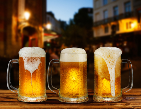 cold glass mug of beer with foam on the background of the streetの写真素材