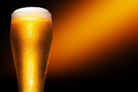 Glass of cold craft light beer on dark background.の写真素材