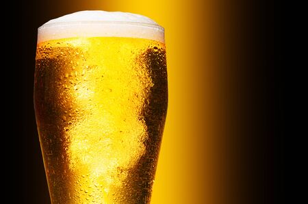 Glass of cold craft light beer on dark background.の写真素材