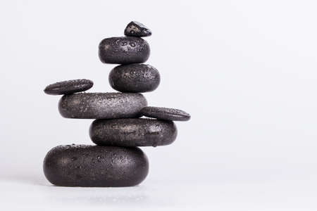 Wet smooth polished hot massage black stones covered with water drops