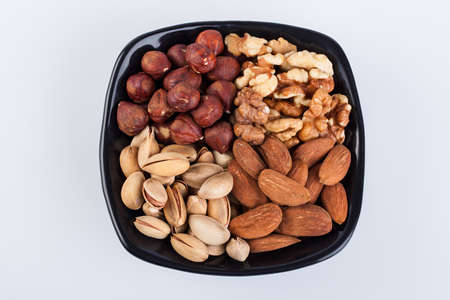 Assorted nuts in ceramic bowl on white background