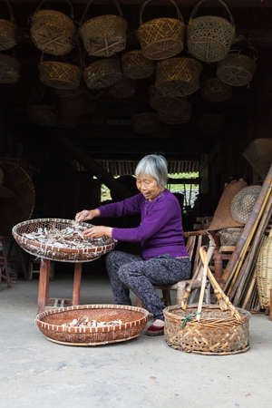 Wenzhou, China - April 04, 2016 Chinese woman farmer works hard selecting good and dried bamboo. Chinese vilage. Old chenesse womanのeditorial素材