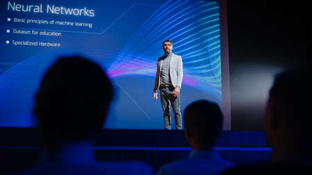 On Stage Speaker Does Presentation of New Product, Uses Remote Control for Presentation, Showing Infographics, Statistics Animation on Big Screen. Live Event / Device Start-up Releaseの写真素材