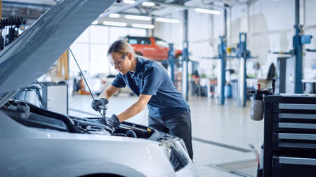 Beautiful Empowering Female Mechanic is Working on a Car in a Car Service. Woman in Safety Glasses...