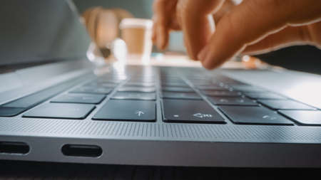 Close-up Moving Macro Shot: Person Typing on Laptop Keyboard. Working, Writing Emails, Using Internet. Notebook lying on the Table, Bright Sunny day in Backgroundの写真素材