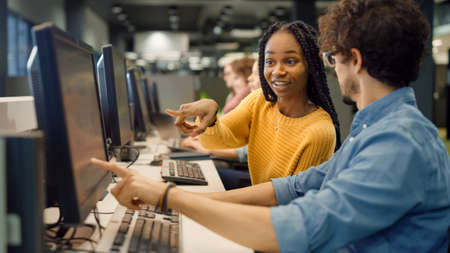 Bright Black Girl and Smart Hispanic Boy Together Work on Computers, Chat, Discuss Class Assignment,...
