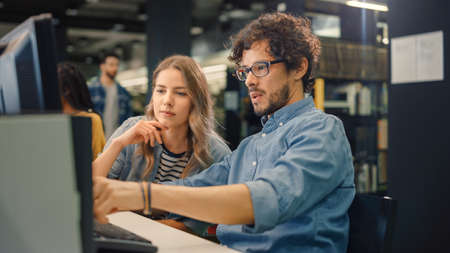 University Library: Bright Caucasian Girl and Smart Boy Together Work on Computers, Chat, Discuss...