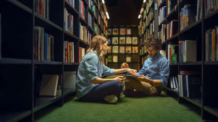 University Library: Smart Caucasian Girl Sitting and Talented Hispanic Boy Sitting Cross-Legged On...