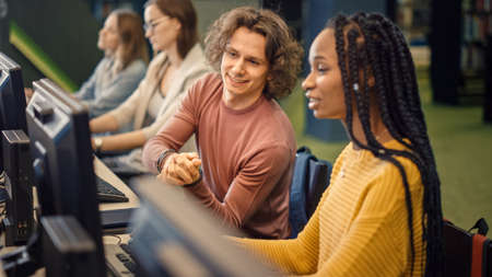 Row of Computer in University Library: Focused Bright Caucasian Boy and Talented Black Girl Study...