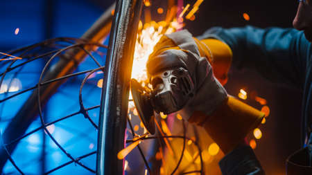 Close Up of a Talented Innovative Artist Using an Angle Grinder to Make an Abstract, Brutal and Expressive Metal Sculpture in a Workshop. Contemporary Fabricator Creating Modern Steel Art.の写真素材