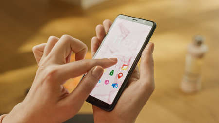 Close-up POV: Woman Uses Smartphone. She Uses Gesture and Taps on the Screen. The Background is...