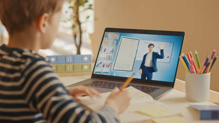 Smart Little Boy Uses Laptop for Video Call with His Teacher. Screen Shows Online Lecture with...