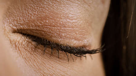 Close Up Macro Shot of an Closed Eye. Young Beatiful Female With Closed Eye. Mascara is Applied to Eyelashes. Dilating Black Pupil.の写真素材