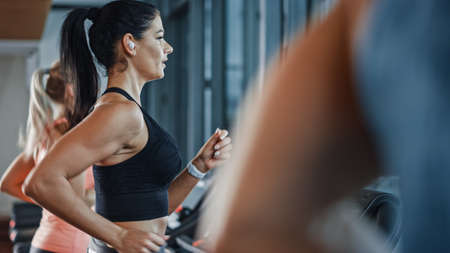 Beautiful Athletic Sports Woman Wearing Wireless Headphones, Listens to a Podcast or Sport Music...