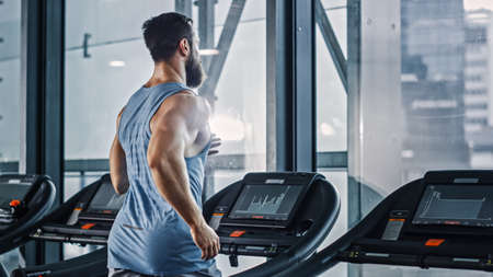 Athletic Muscular Man Running on a Treadmill, Leg and Cardio Day. Strong Man Training in the Modern...