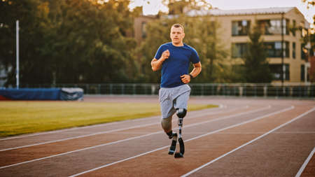 Athletic Disabled Fit Man with Prosthetic Running Blades is Training on a Outdoors Stadium on a...