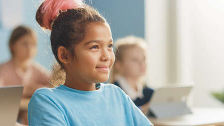 Portrait of a Cute Little Girl with Brown hair Smiling Charmingly and Laughing while Looking at the Teacher.の写真素材