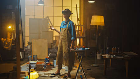 Talented Female Artist Wearing Augmented Reality Headset Working on Abstract Painting, Uses Paint Brush To Create New Concept Art Using Virtual Reality Interface. High tech Creative Modern Studioの写真素材