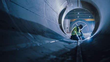 Professional Heavy Industry Welder Working Inside Pipe, Wears Helmet and Starts Welding....