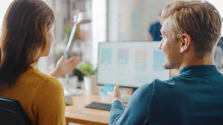 Two Mobile Software Developers Work on Desktop Computer, They Discuss Smartphone Application Design....