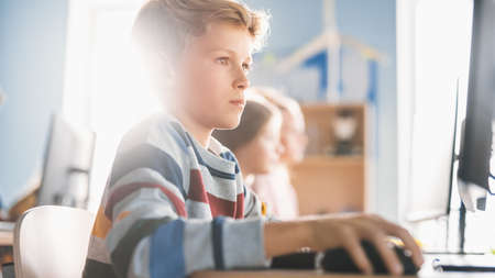 Elementary School Computer Science Classroom: Portrait of a Smart Boy Using Personal Computer, Learning Informatics, Internet Safety, Programming Language for Software Coding. Modern Educationの写真素材