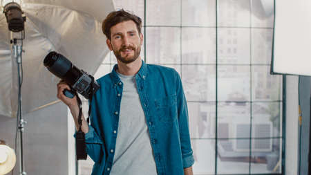 In the Photo Studio with Professional Equipment: Portrait of the Handsome Photographer Holding State...