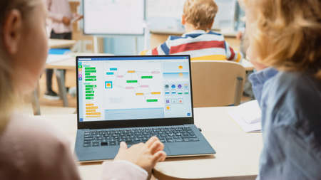 Elementary School Science Class: Over the Shoulder Little Boy and Girl Use Laptop with Screen...