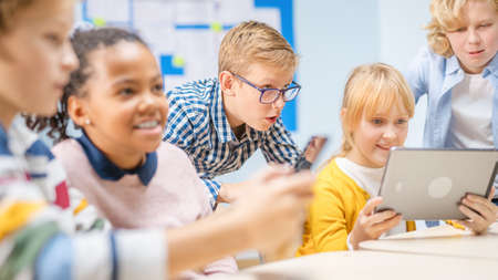 Elementary School Computer Science Class: Children Use Digital Tablet Computers and Smartphones with...