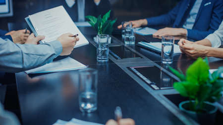 In the Corporate Meeting Room Close-up on the Hands of Businesspeople, Signing Contracts, Using...