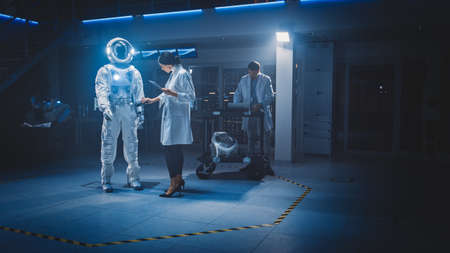 Diverse Team of Aerospace Scientists and Engineers Wearing White Coats Use Computers to Design New Space Suit Adapted for Galaxy Exploration and Travel. Constructing Astronaut Suitの写真素材