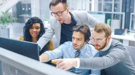 In Modern Office: Diverse Team of Businessmen and Businesswoman Work on Computer, Having Discussion,...
