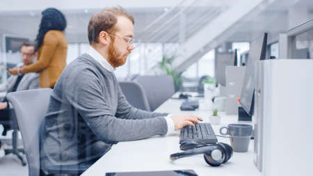 Young Happy Business Salesman Specialist Works with His Desktop Computer in Bright Modern Office. In...