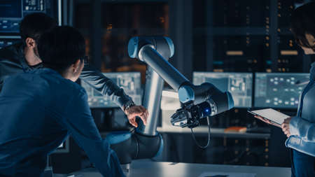 Close Up Vertical Shot of Artificial Intelligence Operating a Futuristic Robotic Arm in a Game of Chess. Robot Moves a Knight. High Tech Modern Research Laboratory.の写真素材