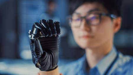 Close Up of a Futuristic Prosthetic Robot Arm Being Tested by a Professional Development Engineer in a High Tech Research Laboratory with Modern Computer Equipment.の写真素材