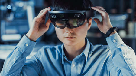 Professional Japanese Electronics Development Engineer in Blue Shirt is Wearing a Virtual Reality...