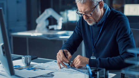 Professional Heavy Industry Engineer Draws Engine Concept Blueprint, References Computer. Engineering Bureau and Industrial Design Laboratory with Various Components in Sightの写真素材
