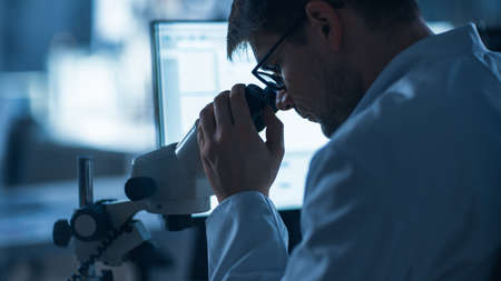 Shot of a Male IT Scientist Uses Computer with Electronic Microscope. In the Background Technology...