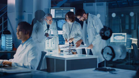 In Technology Research Laboratory: Diverse Team of Industrial Scientists, Engineers, Developers Work with Digital Whiteboard Showing Engine Blueprints, Efficiency Calculated by Neural Networkの写真素材
