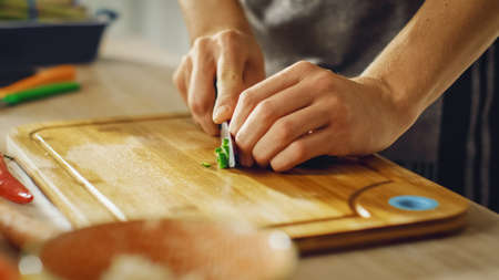 Close Up Shot of a Man Chopping a Green Chili Pepper with a Sharp Kitchen Knife. Preparing a Healthy...