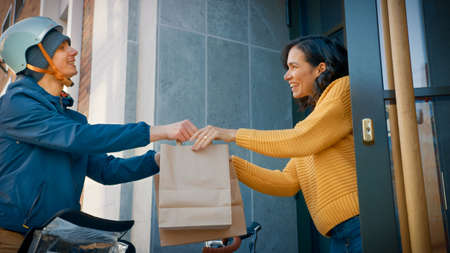 Happy Food Delivery Man on a Bike Delivers Restaurant Order to a Beautiful Female Customer. Courier...