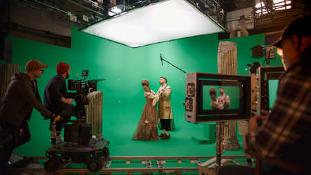 On Big Film Studio Professional Crew Shooting Period Costume Drama Movie. On Set: Director Controls Cameraman Shooting Green Screen Scene with Two Actors Talented Wearing Renaissance Clothes Talkingの写真素材