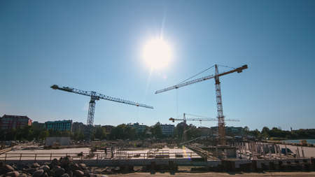 Shot of a Large Real Estate Construction Site with Multiple Operational Tower Cranes. Heavy Machinery and Construction General Workers in Hard Hats and Safety Vests in the Area.の写真素材