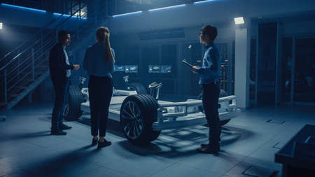 Team of Automobile Design Engineers in Automotive Innovation Facility Working on Electric Car Platform Chassis Prototype that Includes Tires, Suspension, Engine and Battery.の写真素材