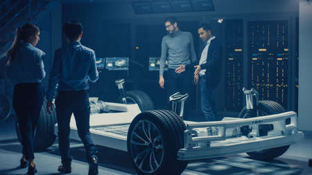 Team of Automotive Engineers Discussing and Designing Electric Car Platform Chassis Prototype,...
