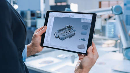 Stylish Female Industrial Robotics Engineer Uses Tablet Computer with CAD Software and to Manipulate...