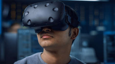 Close-up Portrait of Software Delevoper Wearing Virtual Reality Headset to Develop and Program VR...