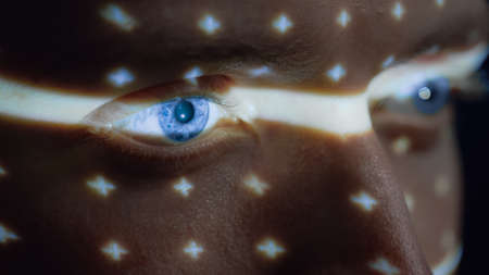 Biometric Facial Recognition Scanning of Blue Eyes Iris. Futuristic Concept: Projector Identifies Individual by Illuminating Face by Dots and Scanning with Laser. Close-up Shotの写真素材