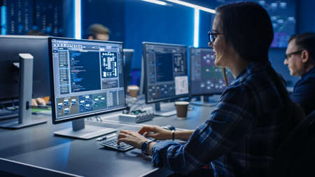 Smart Female IT Programer Working on Desktop Computer in Data Center System Control Room. Team of...