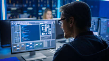 Smart Male IT Programer Working on Desktop Computer in Data Center Technical System Control Room....